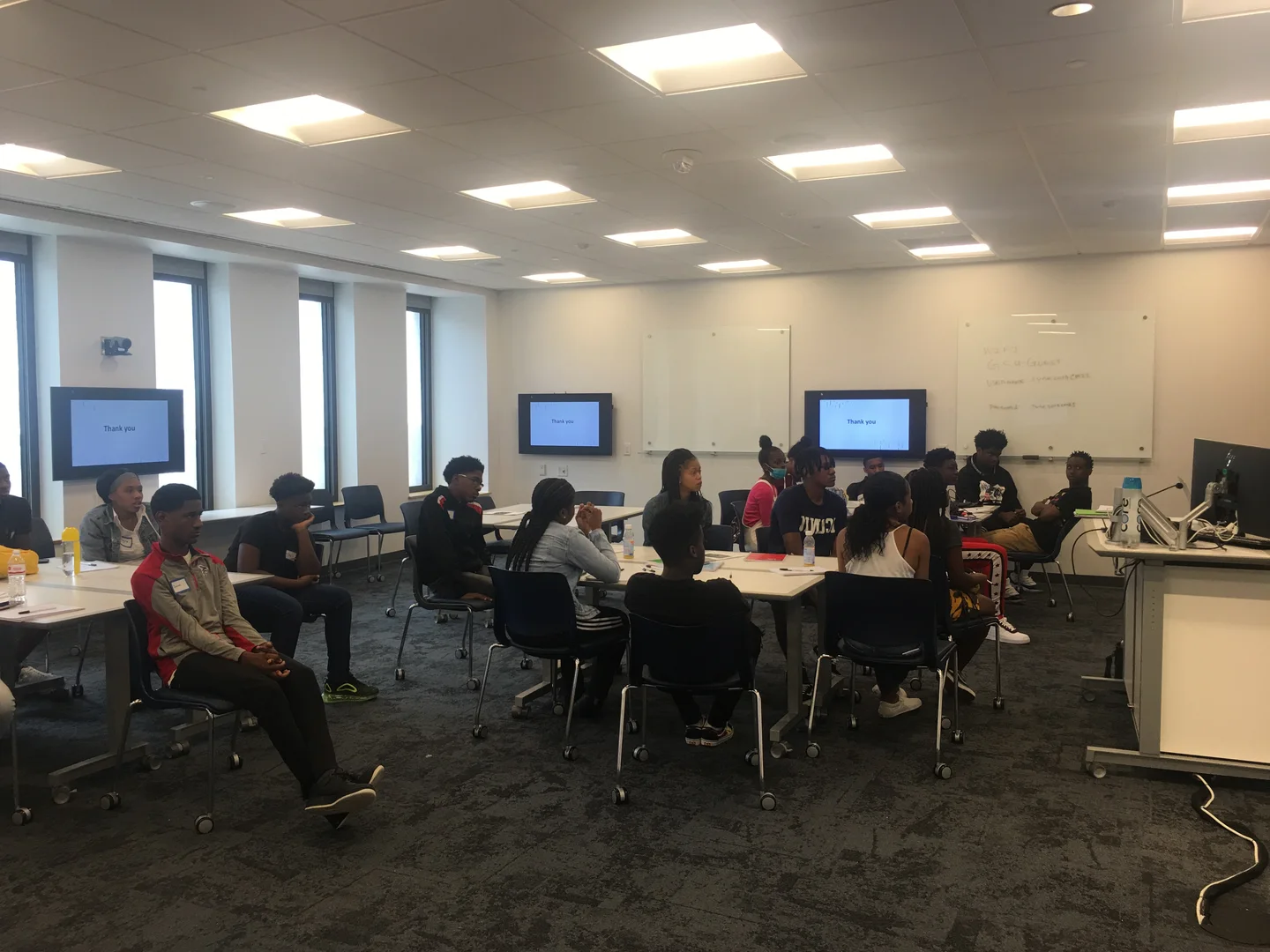 Students gathered around classroom tables during a collaborative program session